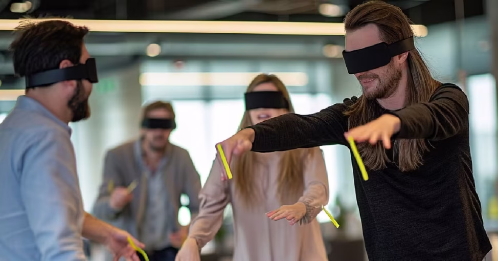 Participant legat la ochi ghidat de un coleg la Blindfold, un joc de comunicare team building.