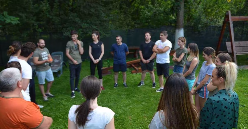Echipă colaborând în natură la Origins, o activitate de supravietuire team building.