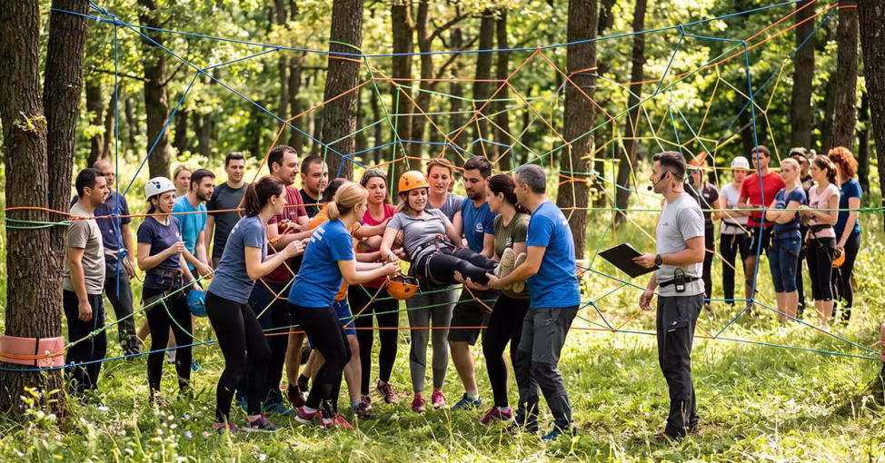Colegi ajutându-se la Panza de Paianjen, un exercitiu de colaborare team building outdoor.