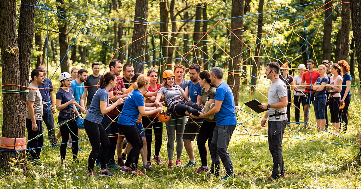 Colegi ajutându-se la Panza de Paianjen, un exercitiu de colaborare team building outdoor.