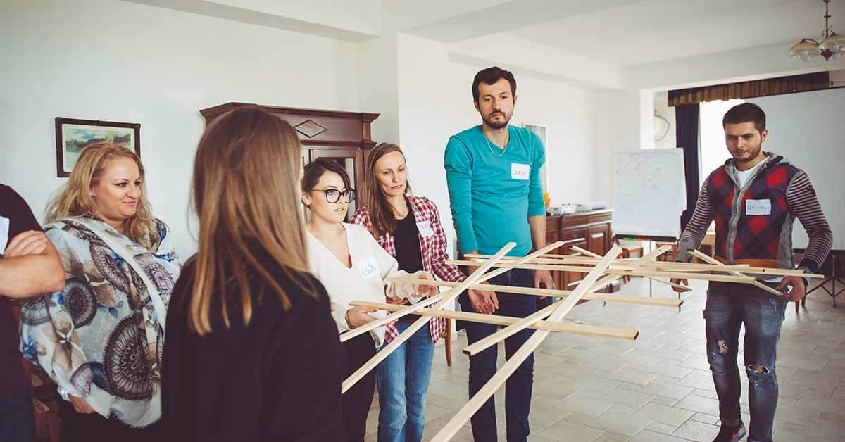Echipă asamblând piese din lemn la Podul lui DaVinci, un exercitiu de logica team building.